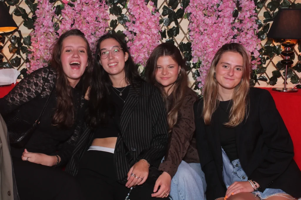 Vier vriendinnen lachend in de caravan photobooth bij de bloemenwand